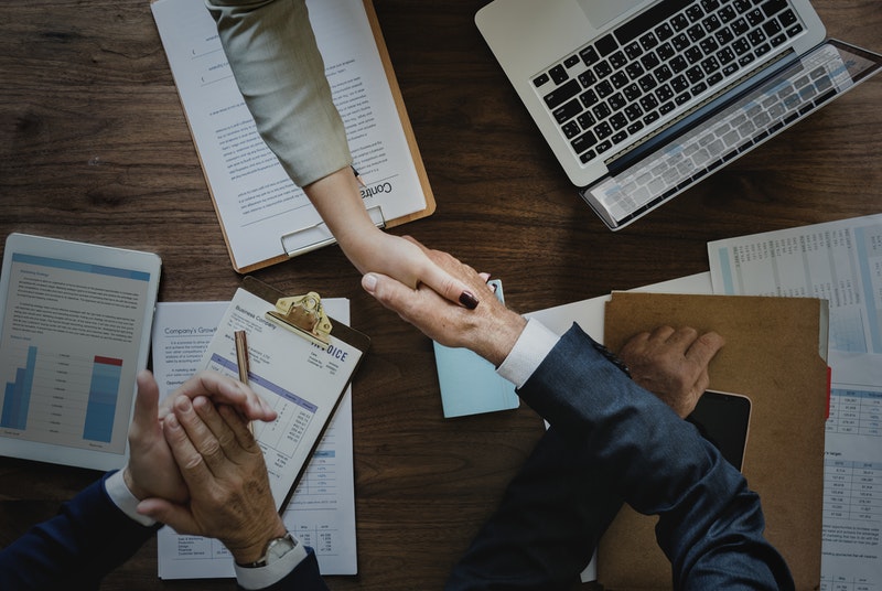 Business clients shaking hands over a desk.